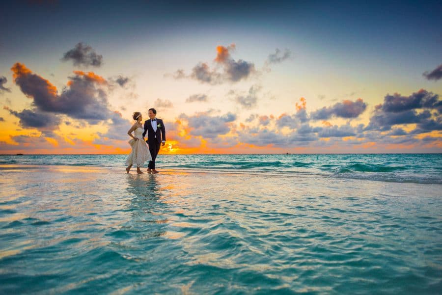 A couple walking together on a beach at sunset
