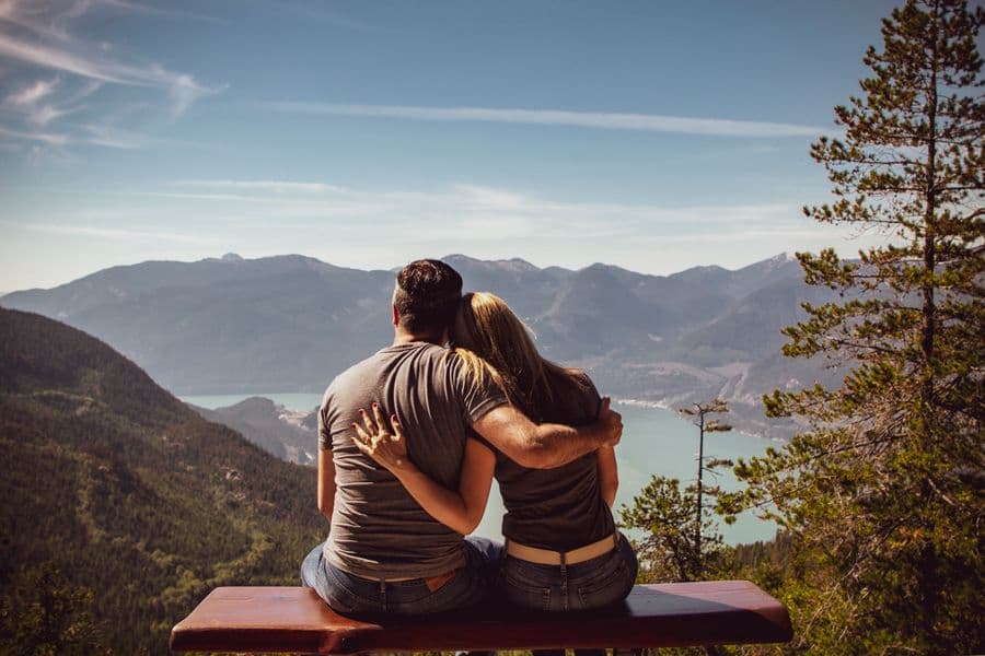 A couple sitting together overlooking a mountain lake